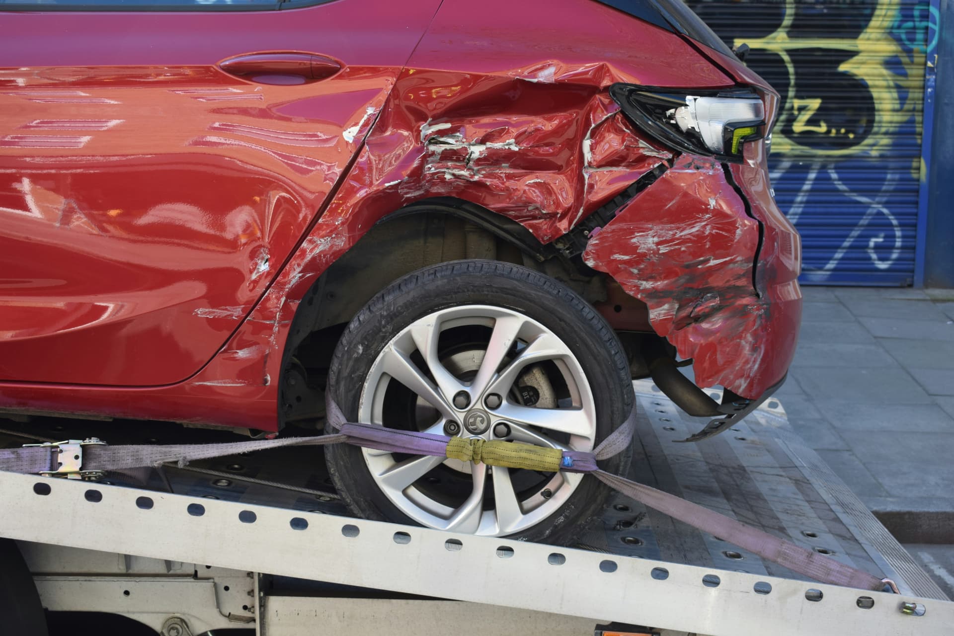 Damaged red vehicle secured on a flatbed recovery truck